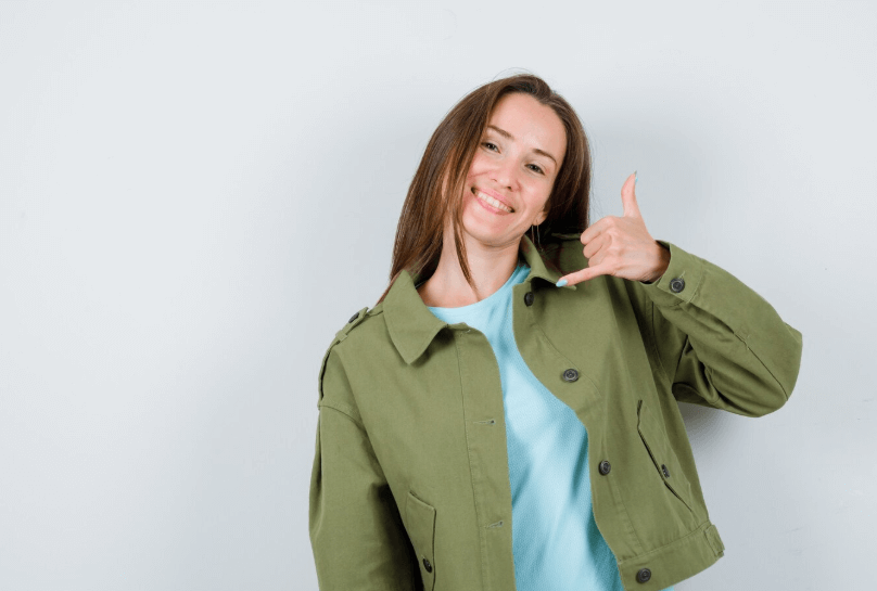 Jeune femme qui fait un signe pour un appel téléphonique, prise de contact avec une assistante administrative